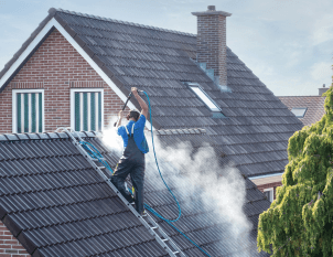 cleaner-with-pressure-washer-at-roof-of-house-cleaning